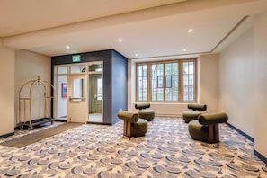 A hotel lobby with a patterned floor, a reception desk, and a large window with a view. - 002 Cook - Loft in the Heart of Old Quebec (Québec)