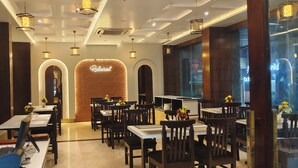 Un interno ristorante con parete in mattoni, diversi tavoli e lampade pendenti.