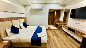 Una camera d'hotel moderna con un letto grande, una TV a schermo piatto, una ventola a soffitto e un pavimento in legno.