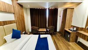 Una camera d'albergo con un letto, una scrivania, una sedia e un angolo cottura.