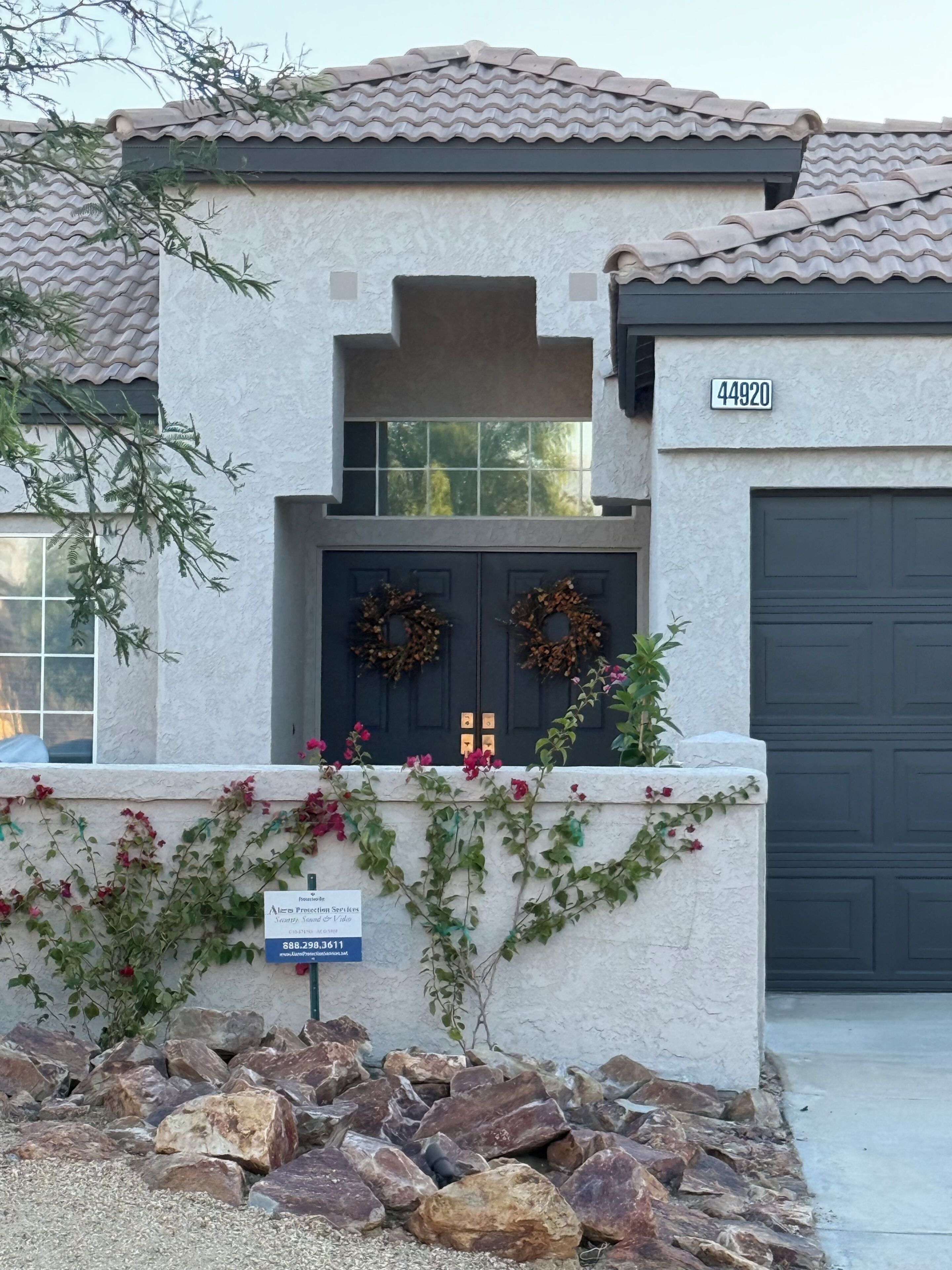 A residential building with a stone facade, a dark garage door, and a number sign.