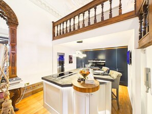 Una cocina moderna con una isla central, electrodomésticos integrados y una escalera de madera.