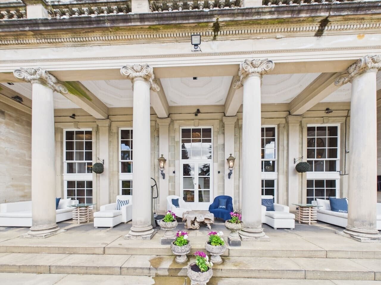 A classical building with a covered entrance, columns, and seating areas with planters.