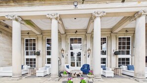 Un edificio in stile classico con un portico, colonne e aree relax con fioriere.