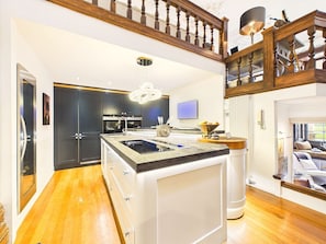 A modern kitchen with a central island, built-in appliances, and a wooden staircase.