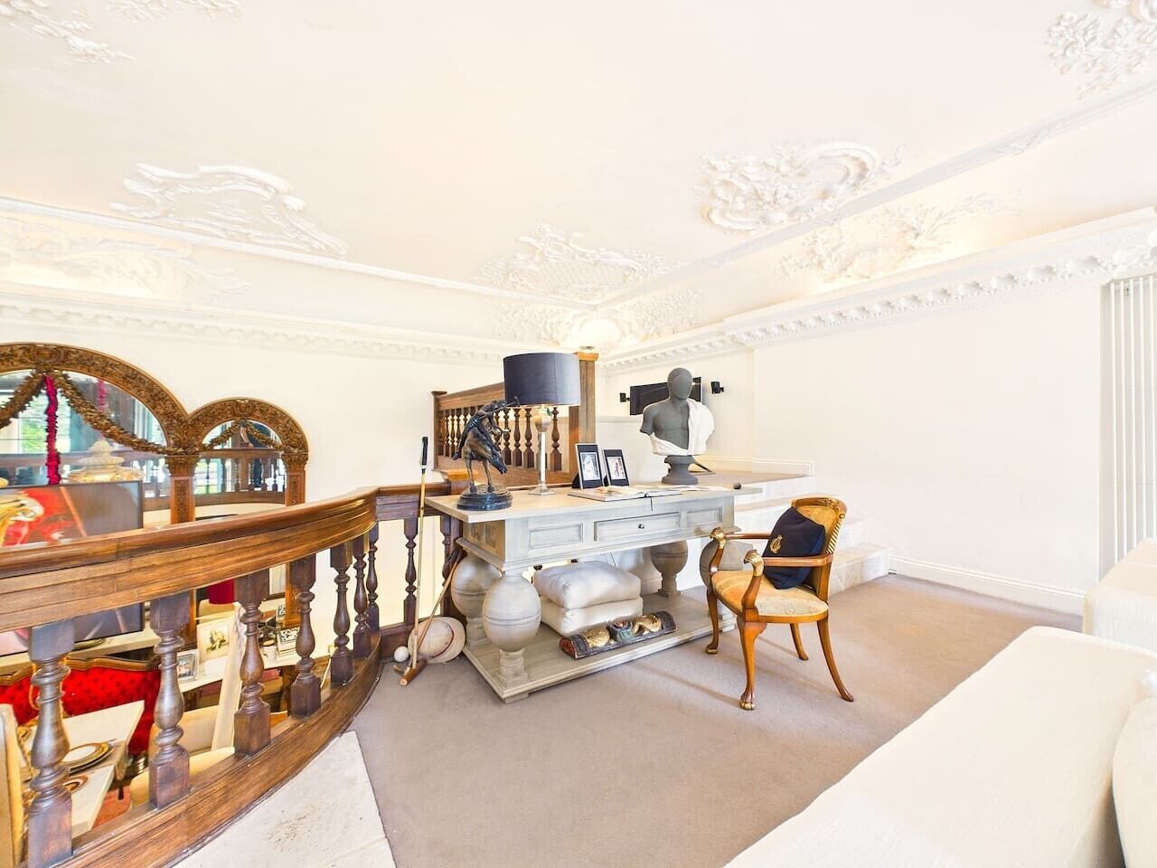 A room with a white sofa, a wooden desk with a lamp, and a chair.