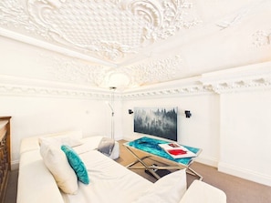 A bedroom with a bed, a glass coffee table, and a painting on the wall.
