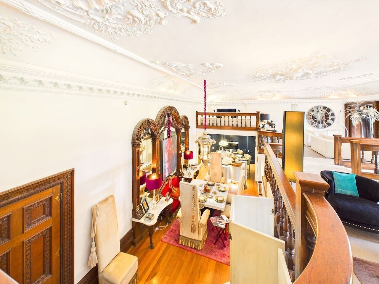 Un interior espacioso con techo alto, detalles de madera ornamentada y una imponente escalera.