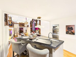 Una cocina moderna con una isla central, taburetes de bar y una lámpara colgante.
