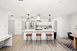 A modern kitchen with a central island, bar stools, pendant lighting, and a dining area with a table and chairs. - Country Retreat home with Private pool,Near Orlando International Airport (Kissimmee)