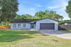 A single-story house with a garage, a front yard, and a wooden fence. - Country Retreat home with Private pool,Near Orlando International Airport (Kissimmee)