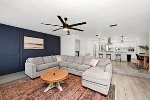A modern living room with a sectional sofa, a round coffee table, and a ceiling fan. - Country Retreat home with Private pool,Near Orlando International Airport (Kissimmee)
