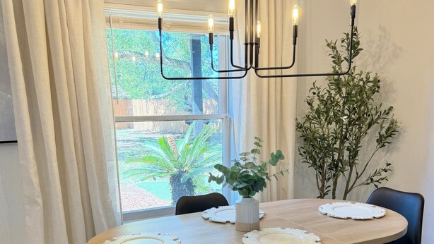 A dining area with a round table, black chairs, a vase with plants, and a window with curtains. - Country Retreat home with Private pool,Near Orlando International Airport (Kissimmee)