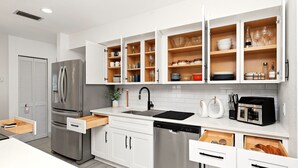 A modern kitchen with white cabinetry, a stainless steel refrigerator, and a built-in dishwasher. - Country Retreat home with Private pool,Near Orlando International Airport (Kissimmee)