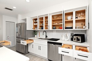 A modern kitchen with white cabinetry, a stainless steel refrigerator, and a built-in dishwasher. - Country Retreat home with Private pool,Near Orlando International Airport (Kissimmee)