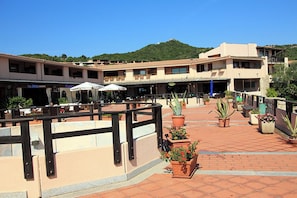 An outdoor patio area with multiple tables and chairs, potted plants, and a wooden fence. - Ground-floor beach house with a garden and beach; pets allowed (Cannigione di Arzachena)