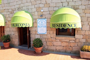 A building with two entrances, each with a green awning and a sign indicating a reception area.