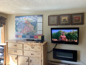 A room with a large map on the wall, a television, and a wooden dresser. - Roomy studio on the bus line in Winter Park with gym, pool, and hot tub (Winter Park)