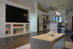 A modern living room with a flat-screen TV, a marble coffee table, and a kitchen area with a refrigerator and oven. - Our Serenity Cove with a private pool in Cape Coral. (Cape Coral)