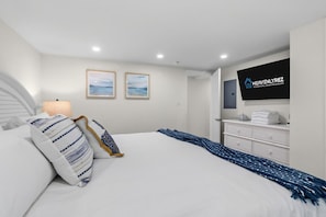 A hotel room with a bed, a television, a dresser, and two framed pictures on the wall. - North End 1BR/1BA Unit 3 - Walk to Beach & Boardwalk (Ocean City)