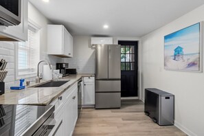 Una cocina moderna con electrodomésticos de acero inoxidable, armarios blancos y vistas al exterior.