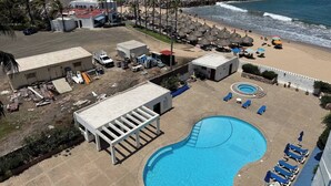 Ein Poolbereich mit Liegestühlen und einem kleinen Pool, umgeben von Strand und Meerblick.