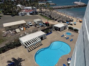 Ein Resort mit Schwimmbad, Liegestühlen und Strand.