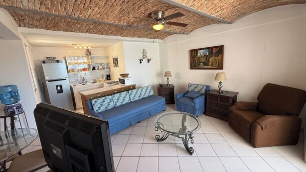 Ein Wohnzimmer mit einer Couch, Sesseln, einem Couchtisch und einem Fernseher.