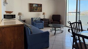 Ein Wohnzimmer mit einer Couch, Sesseln, einem Couchtisch und einem Gemälde an der Wand.