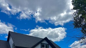 A two-story house with a dark roof, white siding, and a front porch. - The Ruby Ranch House nestled behind Peyton Lake (Indianapolis)