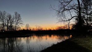 A calm lake at dusk with bare trees silhouetted against the sky. - The Ruby Ranch House nestled behind Peyton Lake (Indianapolis)