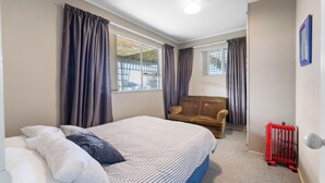Un dormitorio con cama, sofá, radiador y ventana con cortinas.