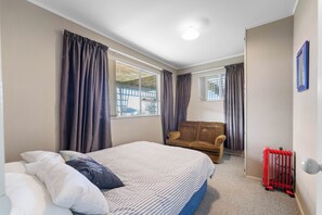 Ein Schlafzimmer mit einem Bett, einem Sofa, einem Heizkörper und einem Fenster mit Vorhängen.