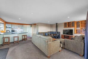 A modern living room with a fireplace, a kitchen area with wooden cabinets, and a bar counter.