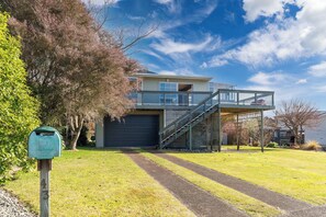 Ein zweigeschossiges Haus mit Garage und überdachter Veranda, bewölkter Himmel.