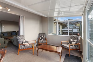 A modern living room with a glass ceiling, a wooden coffee table, and patterned armchairs.
