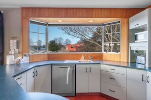 A modern kitchen with a large window, a dishwasher, and a microwave. - JOE'S Getaway - Omori Holiday Home (Omori)
