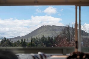 A view from inside a vehicle, looking out at a mountain with a forested base and a clear sky with clouds. - JOE'S Getaway - Omori Holiday Home (Omori)