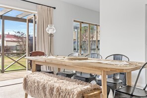 A dining area with a wooden table, chairs, and a bench. - Meadowstone Vista - Wanaka Holiday Home (Wanaka)
