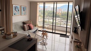 A modern living room with a large window, a sofa, a coffee table, and a TV. - Apto Oasis Sabaneta / Enjoyment and Well-Being (Sabaneta)
