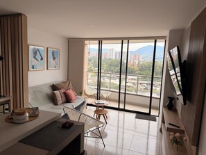 Ein modernes Wohnzimmer mit großem Fenster, einer Couch, einem Couchtisch und einem Fernseher.