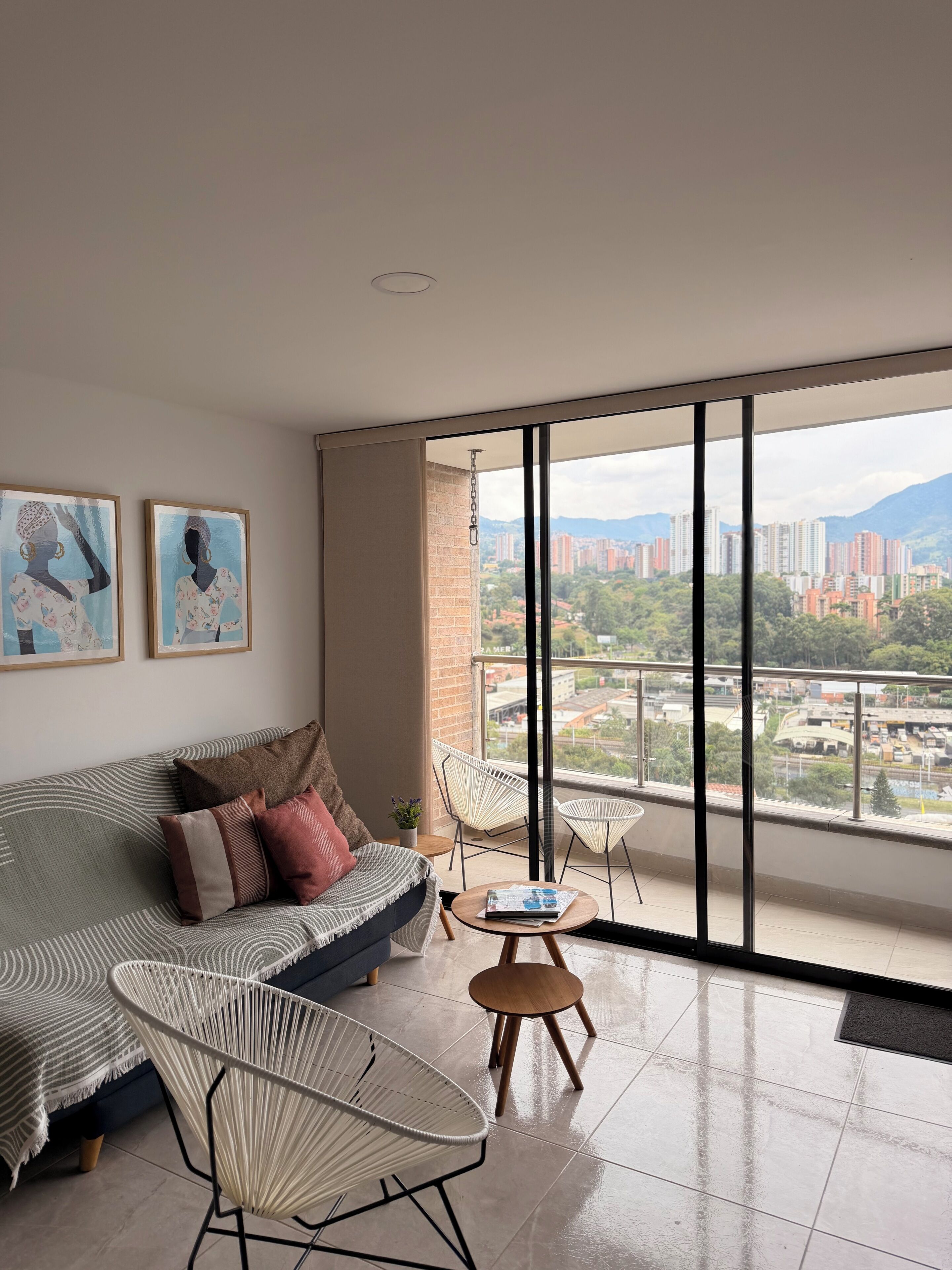 A modern living room with a sofa, two armchairs, a small table, and artwork on the wall.