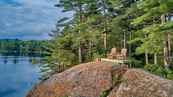 A lakeside cabin with a deck and outdoor seating.