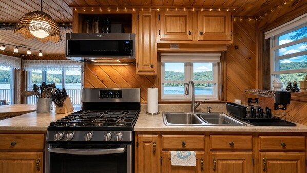 A kitchen with a stove, sink, and wooden cabinets.
