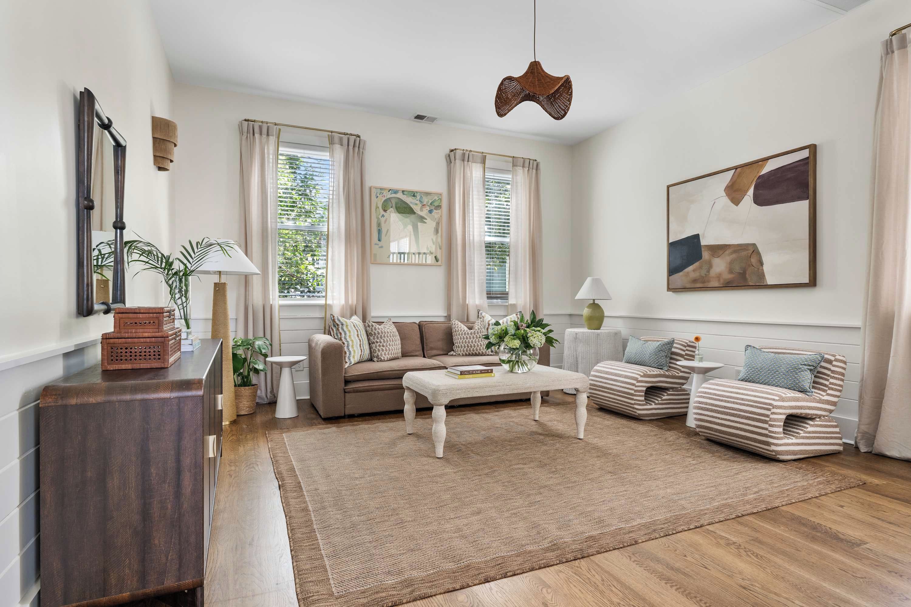 A living room with a sofa set, a coffee table, a side table, and a hanging light fixture.