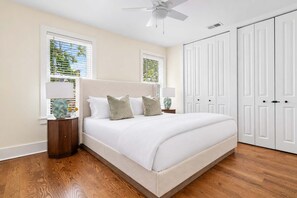 A bedroom with a bed, nightstands, a ceiling fan, and white wardrobes. - Brand New - Downtown 2 Bedroom (Charleston)