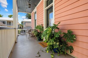 Une véranda avec une balustrade en bois, des plantes en pot et un paillasson.