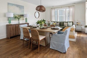 A dining area with a wooden table, woven chairs, and a hanging light fixture. - Spacious 4bd w. Balconies, Heart of Downtown! (Charleston)