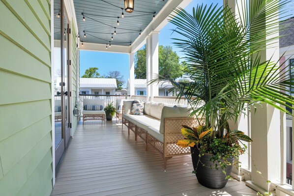 A covered porch with outdoor seating and potted plants.