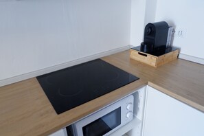 A kitchen with a wooden countertop, a black induction cooktop, a white microwave, and a coffee maker on a wooden stand. - La Casina in Massa: a house for 6 with parking, near the beach (Massa)